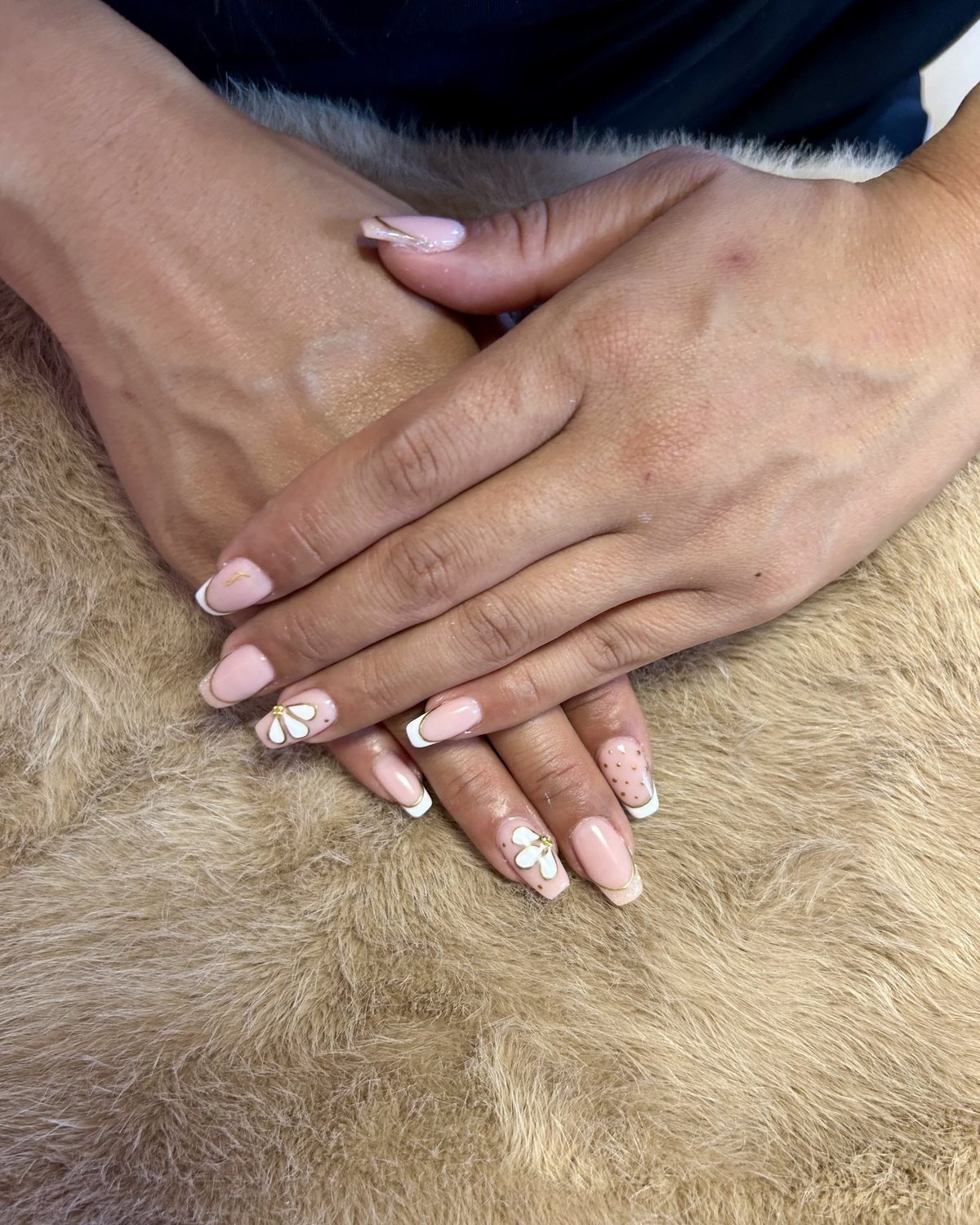 Nude-roze nagels met witte French-randjes, witte 3D-bloemetjes met een gouden hart en stipjes
