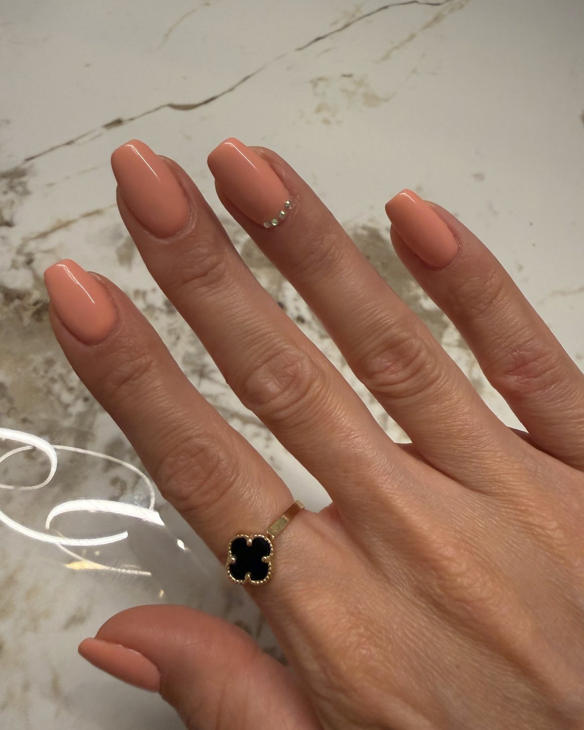 Perzikkleurige gellak met een rijtje kleine steentjes op één nagel